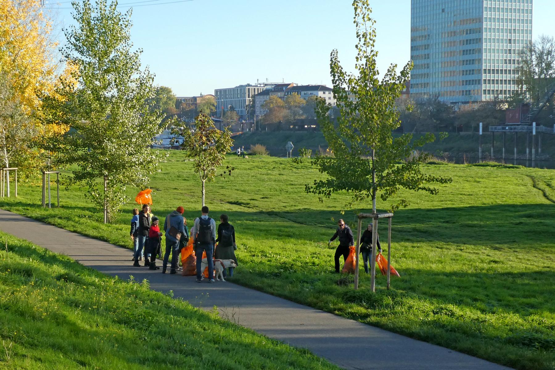 Menschen am Neckarufer mit gelben Müllsäcken