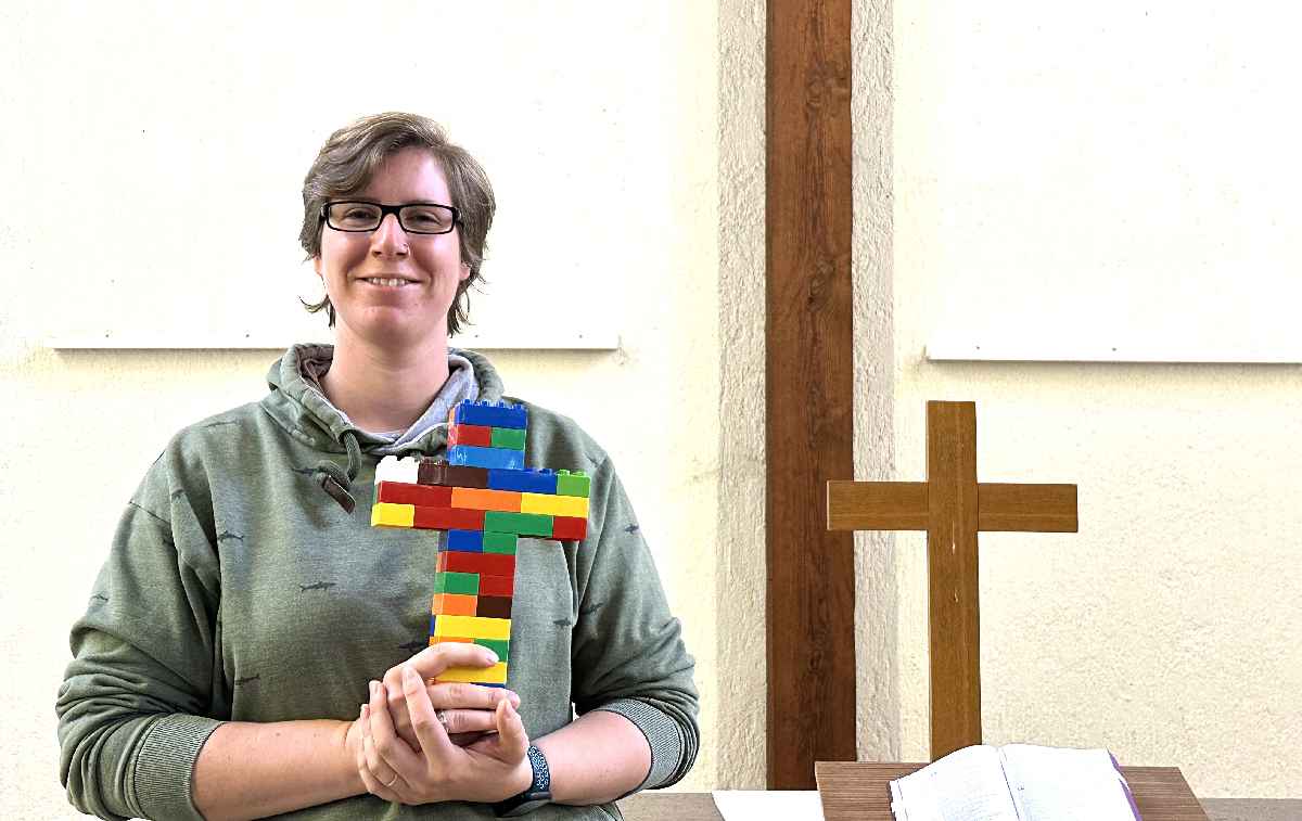 Svenja Hauseur hält ein Kreuz aus Lego-Steinen in der Hand.