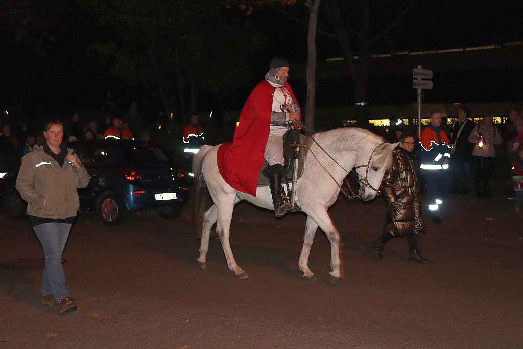 Reiter im roten Mantel sitzt auf weißem Pferd