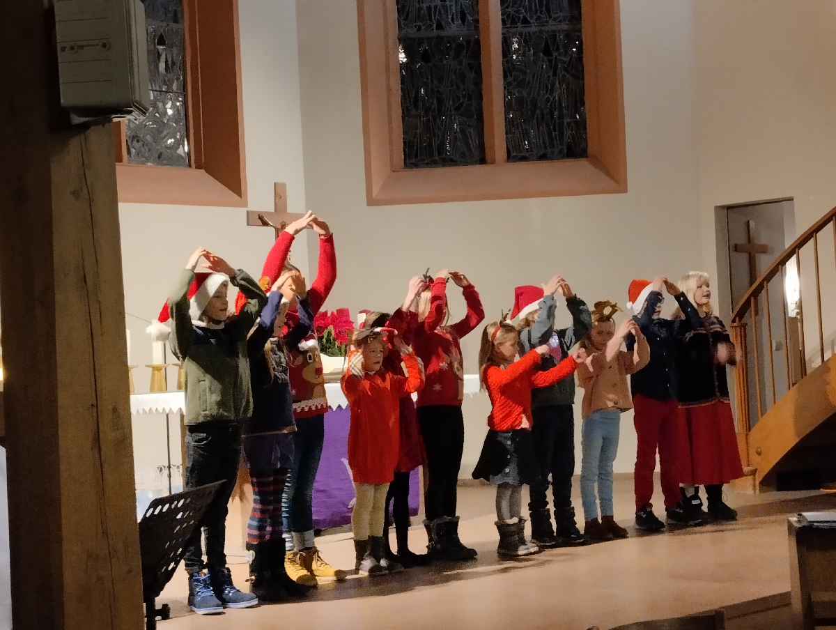 Kinder mit Nikolausmützen singen in der Kirche